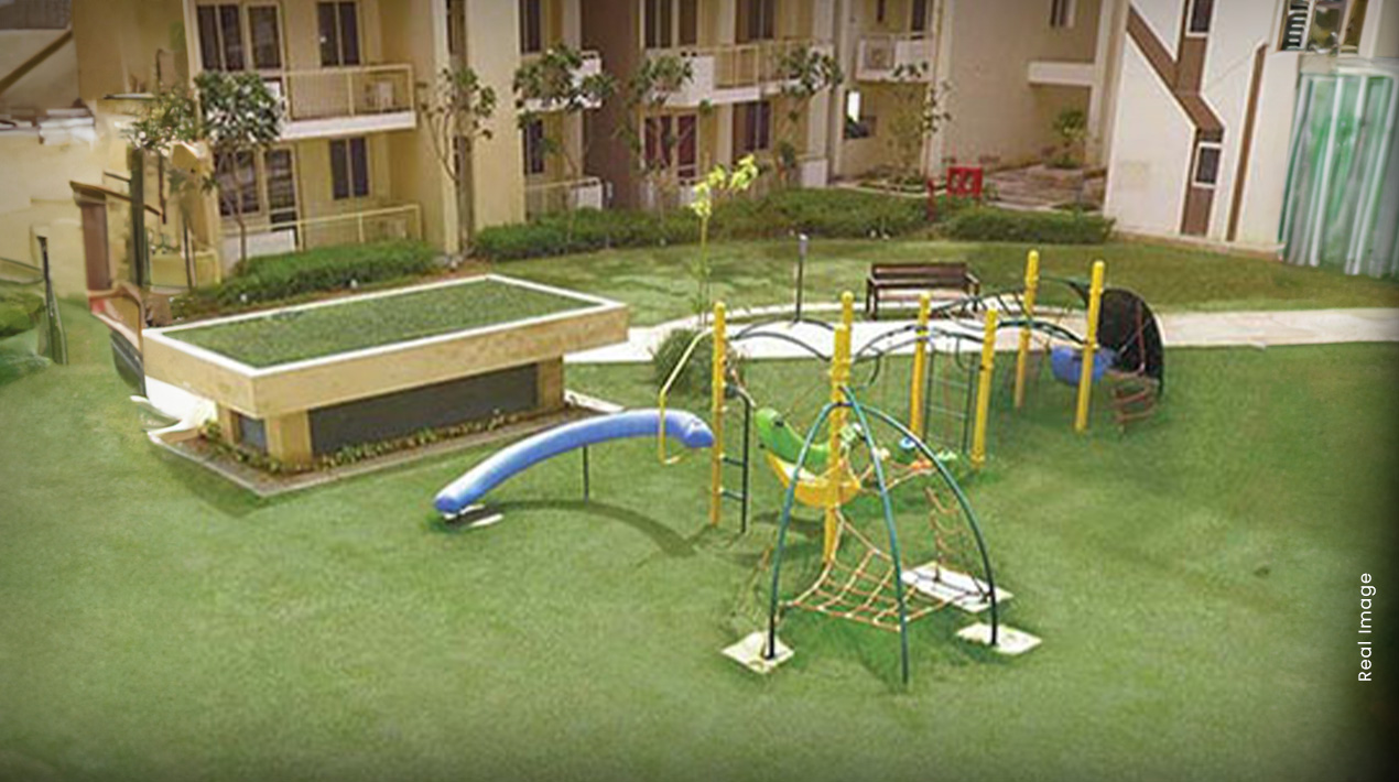 Children's play area with swings, slides and manicured green lawns at M3M Woodshire Sector 107